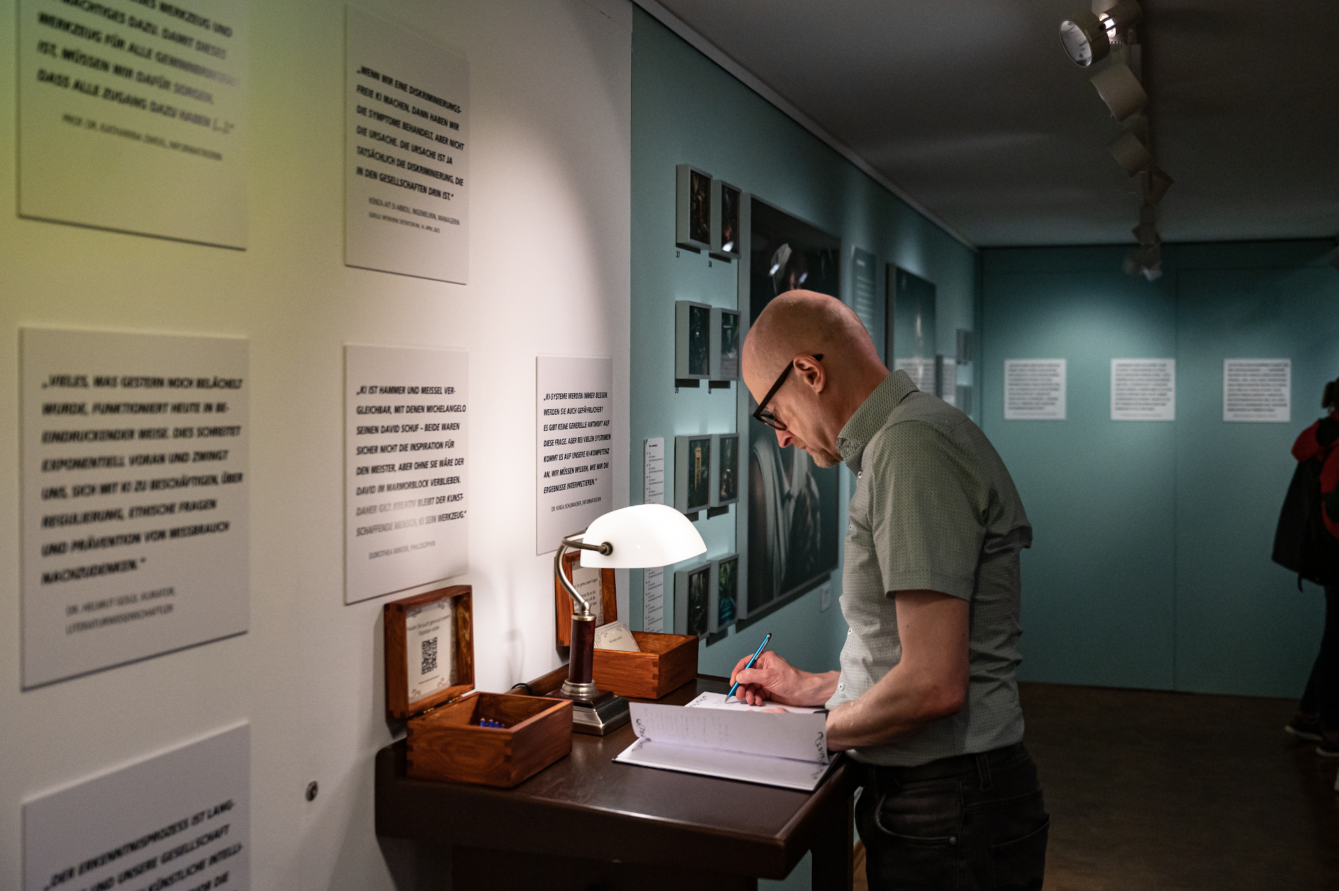 Blick in die Ausstellung "New Realities - Wie Künstliche Intelligenz und abbildet" im Museum für Kommunikation Nürnberg. Ein Besucher schreibt seine Gedanken zu Künstlicher Intelligenz auf einen Zettel für das Visitor Board